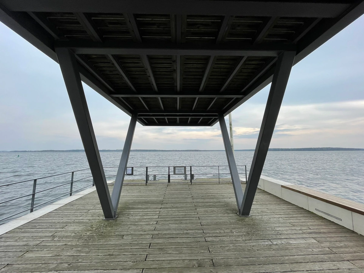 Überdachter Steg am Stadthafen Senftenberg mit Blick auf den Senftenberger See an einem grauen Märztag